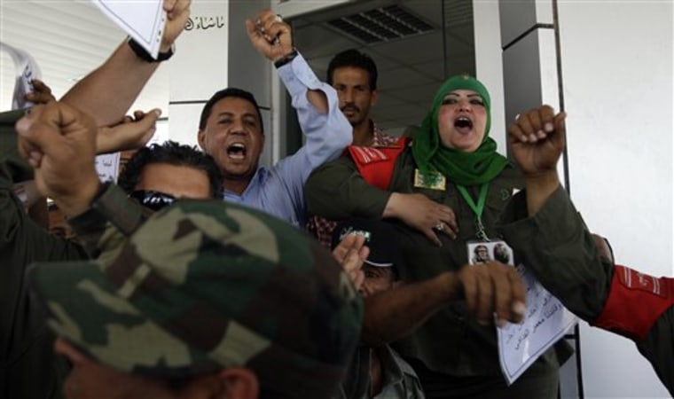 In this Sunday, May 29, 2011 file photo, Ibtisam Saadeddin, 35, right, a khaki-clad female soldier wearing a green Muslim headscarf and Libyan leader Moammar Gadhafi's pin on it, shouts pro-Gadhafi chants at the women-only Gurji fuel station in Tripoli, Libya. (AP Photo/Ivan Sekretarev, File)